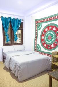 Planet Nomad Hostel في كاتماندو: سريرين في غرفة بيضاء مع ستائر زرقاء