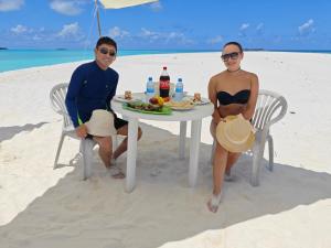 two people sitting at a table on the beach at Dhonfulhafi Beach View in Maalhos