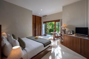 a bedroom with a large white bed and a television at Tapa Tepi Kali Canggu in Canggu