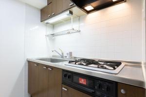 a kitchen with a stove and a sink at Raiwa Mansion Minami Azabu in Tokyo
