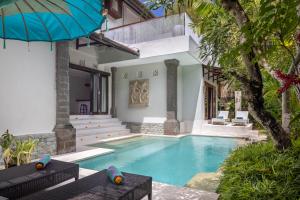 a villa with a swimming pool and a house at Tapa Tepi Kali Canggu in Canggu