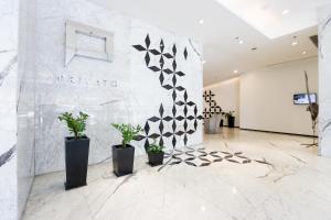 a lobby with potted plants and a wall at Privato Ortigas in Manila