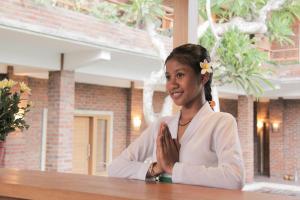 a woman sitting at a table with her hands folded at Govardan Home stay in Canggu