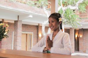 a woman sitting at a table with her hands folded at Govardan Homestay in Canggu