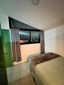 een slaapkamer met een bed en een raam met uitzicht bij Departamento TAPO/Aeropuerto in Mexico-Stad