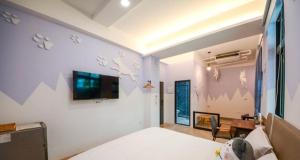 a bedroom with a bed and a tv on the wall at Happy Dog Homestay in Hualien City