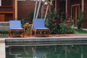 twee blauwe stoelen naast een zwembad met water bij Govardan Home stay in Canggu