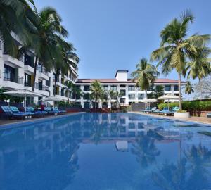 a large swimming pool with palm trees and buildings at Fairfield by Marriott Goa Anjuna in Anjuna