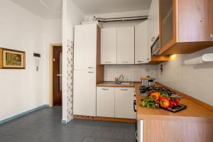 uma cozinha com armários brancos e vegetais num balcão em Casa Cabana - 200m From The Sea - Happy Rentals em Alassio
