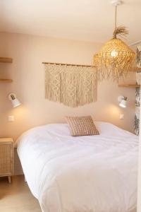 a bedroom with a white bed with a chandelier at Les Voiles - Appart'hotel "Le Kornog" in Carnac
