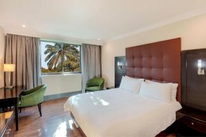 a hotel room with a bed and a desk and a window at Protea Hotel by Marriott Lusaka in Lusaka