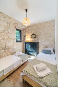 a bedroom with two beds and a stone wall at Fortuna in Nerežišće