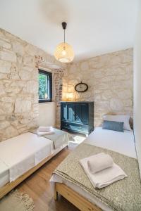 a bedroom with two beds and a stone wall at Fortuna in Nerežišća