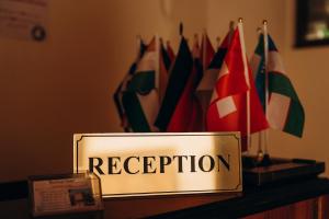 a sign that reads reception on a table with flags at Hotel SHOHRUD in Bukhara