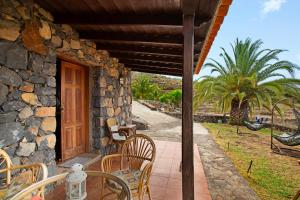a porch of a stone house with a table and chairs at La Roquina in Tijarafe