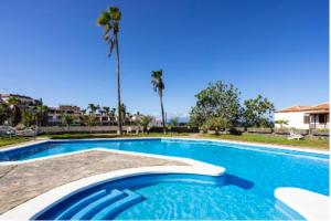 uma piscina azul com palmeiras ao fundo em Ocean View Townhouse em Santiago del Teide