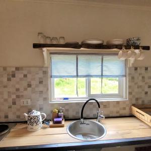eine Küchentheke mit einem Waschbecken und einem Fenster in der Unterkunft Karu-Terra cabin in Huiscapi