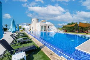 a swimming pool with chairs and a house at Blue Diamond Beach Villas in Paphos City