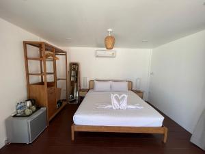a bedroom with a bed with white sheets and a shelf at Nice Sea Resort in Srithanu