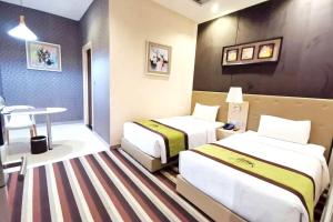 Habitación de hotel con 2 camas y mesa en Capital O 75451 Podstel Hostel Bangkok, en Bangkok