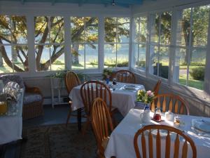 a dining room with tables and chairs and windows at House on Chase Creek in Shelter Island Heights