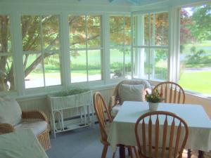 a dining room with a table and chairs and windows at House on Chase Creek in Shelter Island Heights +18 photos