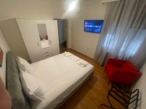 1 dormitorio con 1 cama blanca y 1 silla roja en The Nest, en Tesalónica