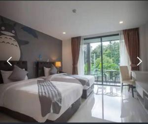 a hotel room with two beds and a balcony at Panwa Beach Side in Phuket Town