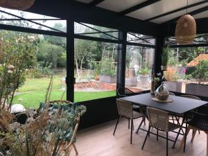 un salón acristalado con mesa y sillas y un jardín en La Grange d'Hélène, en Cholet