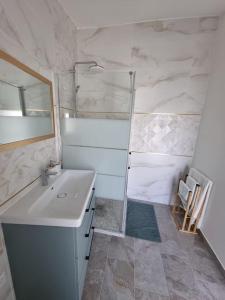 een witte badkamer met een wastafel en een douche bij Charmante petite maison in Le Crès