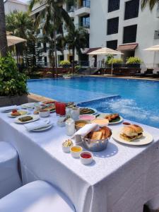 a table with food on it next to a swimming pool at Fairfield by Marriott Goa Anjuna in Anjuna