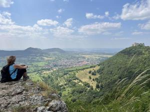 a woman sitting on a rock looking at a valley at Steinach-Apartment-Neuffen in Neuffen
