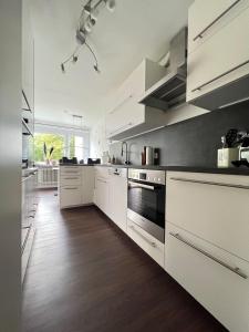 a large kitchen with white cabinets and wood floors at Steinach-Apartment-Neuffen in Neuffen