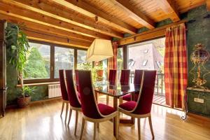 uma sala de jantar com uma mesa de vidro e cadeiras vermelhas em Arroquets em Vielha