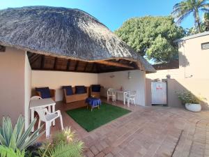 een patio met een rieten dak en een tafel en stoelen bij African Thistle in St Lucia