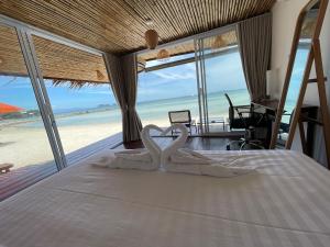 two swans making a heart shape on a bed in a bedroom at Nice Sea Resort in Srithanu