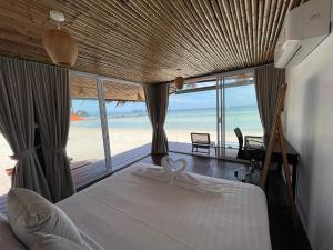 a bedroom with a bed with a view of the beach at Nice Sea Resort in Srithanu