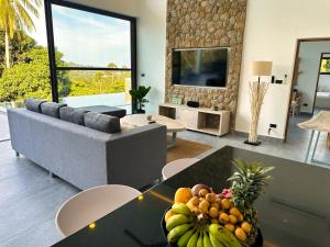 VILLA CAMILLE - SEAVIEW - 4 Bedrooms في كوه ساموي: غرفة معيشة بها أريكة وطاولة عليها فاكهة