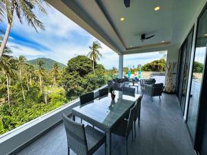 a dining room with tables and chairs and a large window at VILLA CAMILLE - SEAVIEW - 4 Bedrooms in Koh Samui 