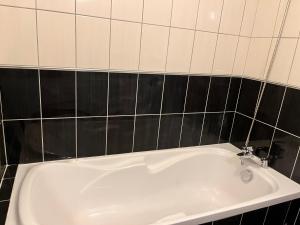 y baño con bañera y azulejos negros. en LE 13’OR, en Beaurepaire