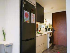 a kitchen with a black refrigerator with stickers on it at Meisterstadt Pollux Habibie in Batam Center