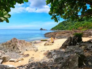 a person standing on a beach with a surfboard at L'Astrolabe - Ocean View Tiny House in Baras