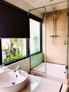 uma casa de banho com um lavatório e um chuveiro com uma porta de vidro em Unique Serviced Apartment em Hanói