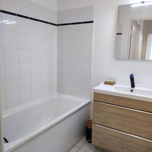 ein weißes Badezimmer mit einer Badewanne und einem Waschbecken in der Unterkunft Montereau FY Appt 3P 2 ch Balcon in Montereau-faut-Yonne