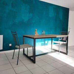 einen Tisch und zwei Stühle in einem Zimmer mit blauer Wand in der Unterkunft Montereau FY Appt 3P 2 ch Balcon in Montereau-faut-Yonne
