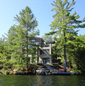 una casa a orillas de un lago con árboles en Gîte et Atelier de L'Artiste Peintre Paysagiste Canadien Gordon Harrison, en Sainte-Marguerite