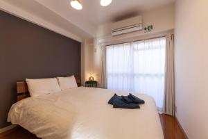 Un dormitorio con una gran cama blanca con ventana. en Chatelet Nishi-Oi, en Tokio