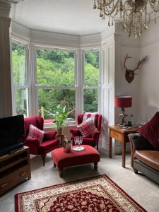 a living room with red chairs and a large window at Heathbank House B&B in Matlock Bank