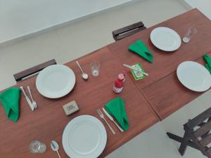 a wooden table with white plates and green napkins at Hotel Serugahawatta in Wellawaya