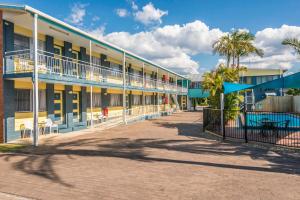 a building with a courtyard with chairs and palm trees at Pacific Motor Inn in Evans Head